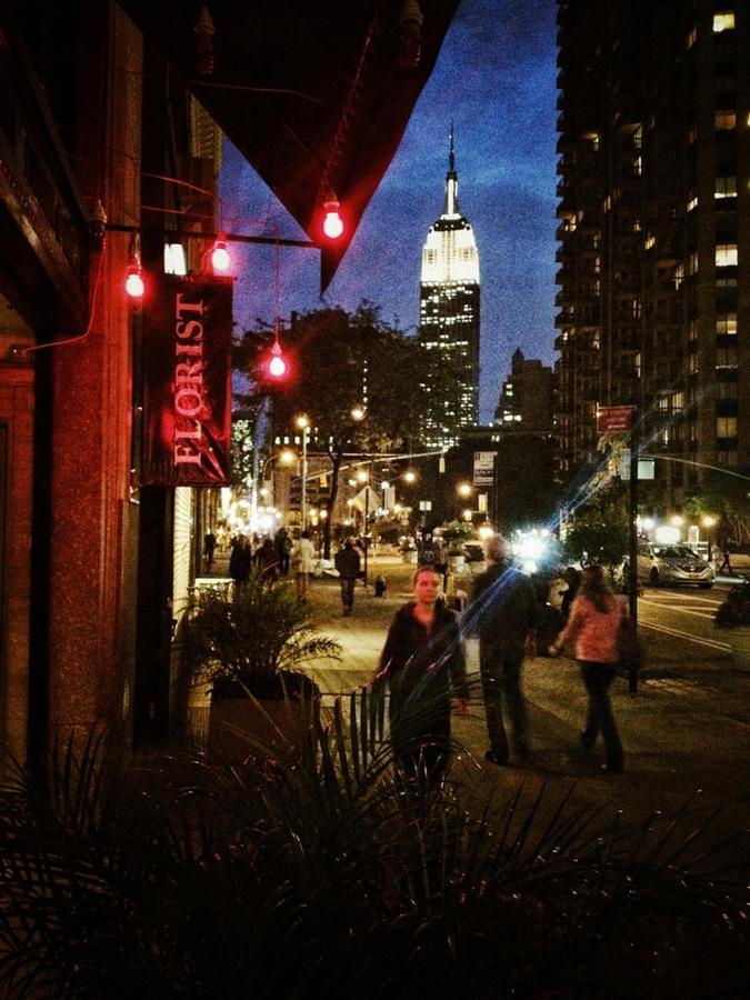 [Image: Florist by @LordOfVisions - Ext. Night: Pedestrians walk by florist, Empire State Building in background. Mood is dreamy. on Propic]